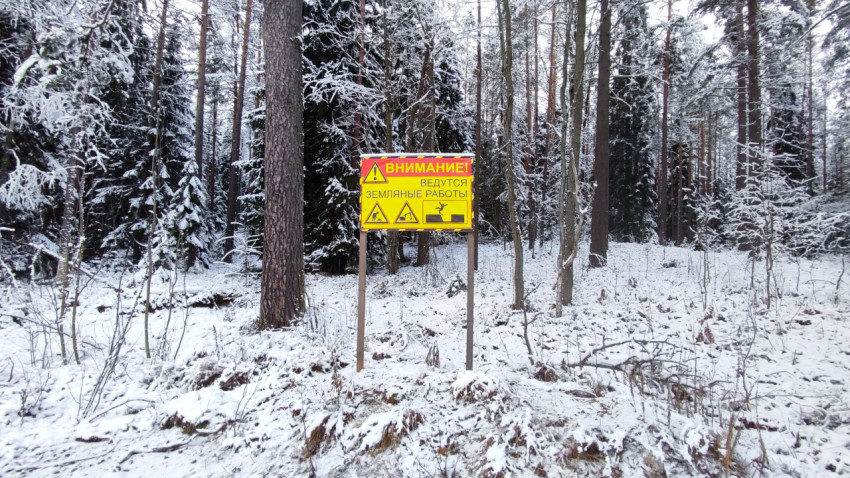 Информационный знак о земляных работах на фоне зимнего леса