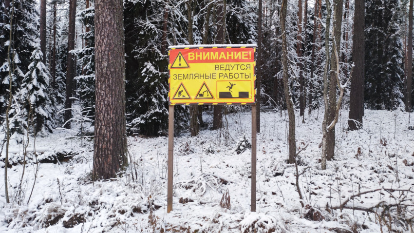 Предупреждающий щит о земляных работах на фоне зимнего леса
