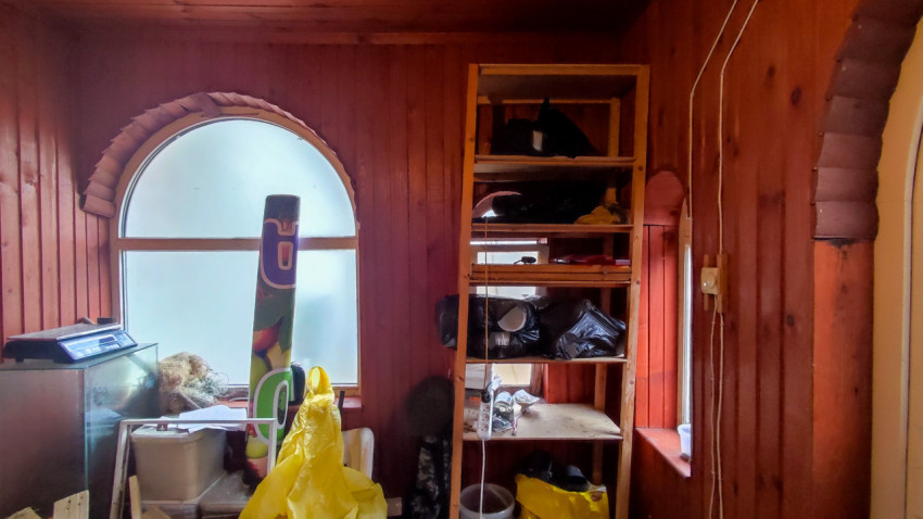 Комната с деревянной отделкой и арочными окнами, используемая как склад