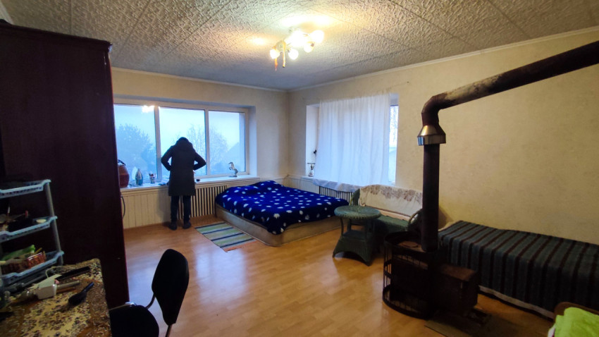 Осмотр жилой комнаты с кроватью и металлической печью