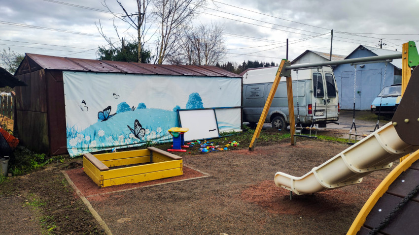 Детская площадка с песочницей и качелями у гаражей