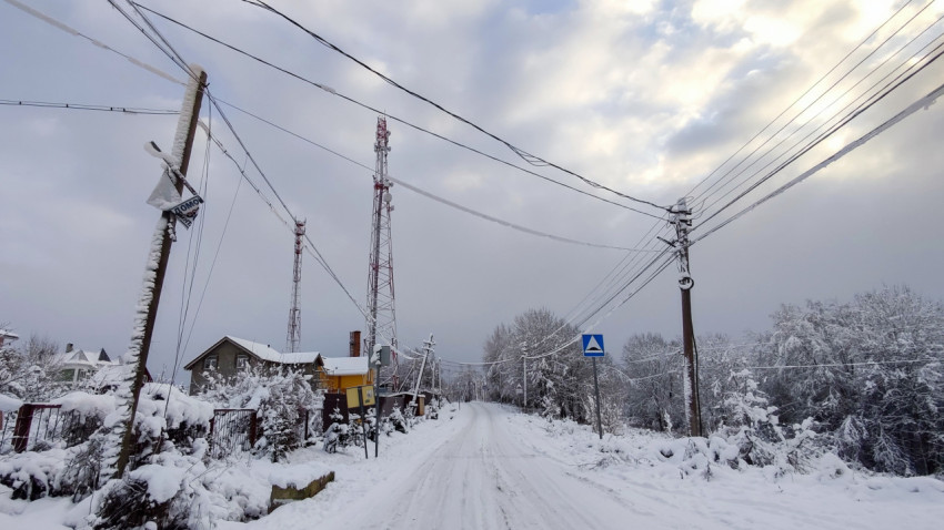 Зимняя загородная улица с линиями связи и опорами электроснабжения