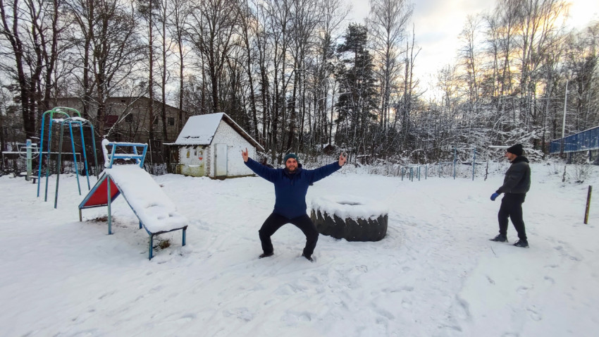 Зимняя детская площадка с людьми на фоне леса