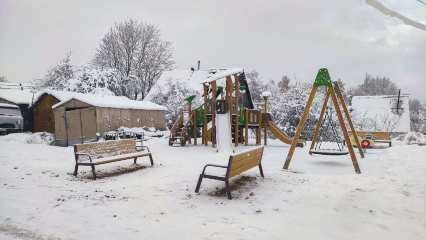 Детская игровая площадка зимой с оборудованием и придомовой территорией