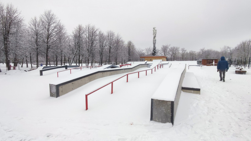 Скейтпарк с бетонными фигурами и перильными элементами зимой
