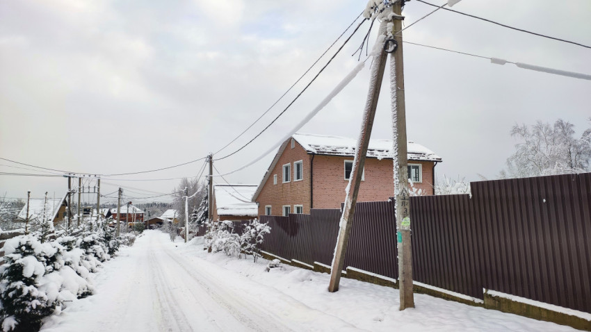 Загородная улица зимой с частной застройкой и линиями электропередачи