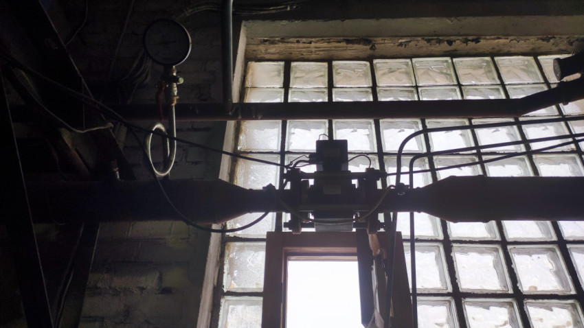 Манометр и трубопровод на фоне окна из стеклоблоков