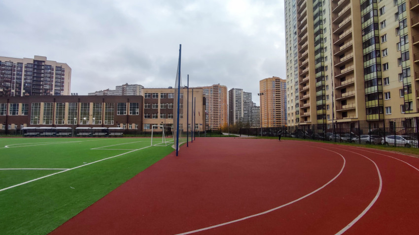 Беговая дорожка и футбольное поле рядом со школьным зданием