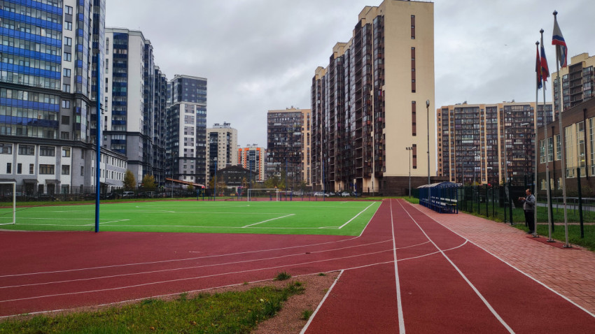 Современное футбольное поле с беговыми дорожками во дворе жилого квартала