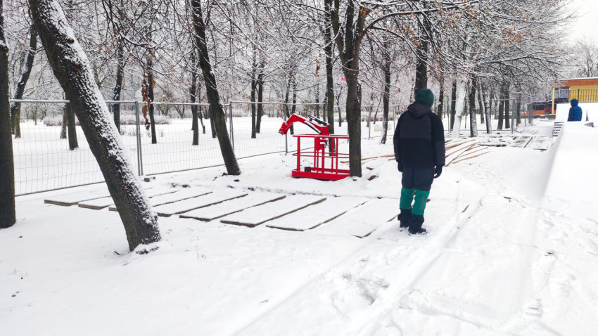 Проход с бетонными плитами и временным ограждением в зимнем парке
