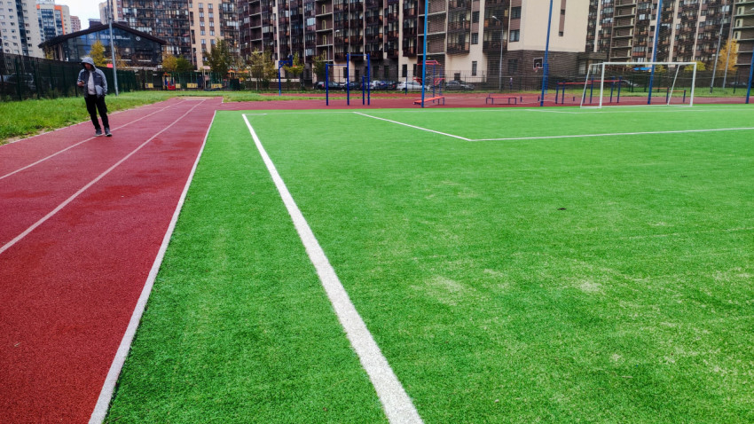 Угловая зона футбольного поля с беговой дорожкой и игроком