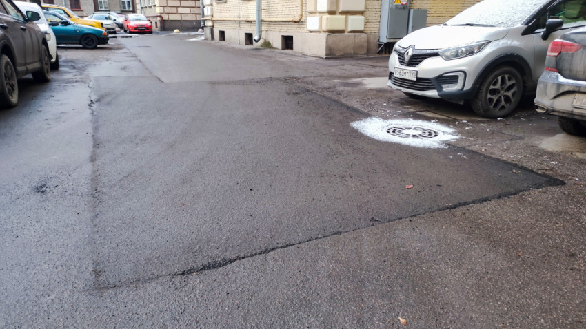 Асфальтовое покрытие с новым люком во дворе жилого дома