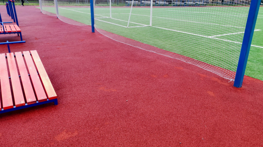 Спортивная площадка с резиновым покрытием и сеткой у футбольного поля