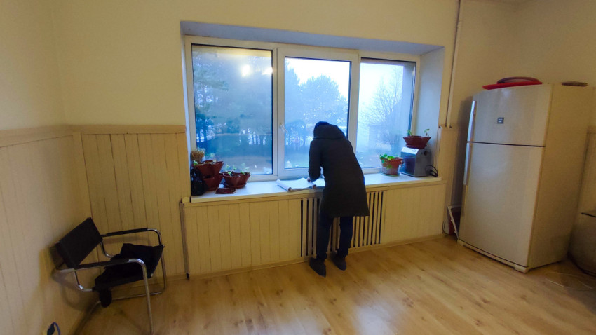 Осмотр комнаты с холодильником и подоконником, заставленным растениями