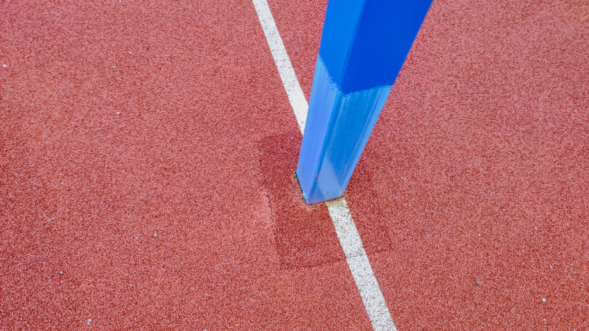 Узел крепления стойки на резиновом покрытии спортивной площадки