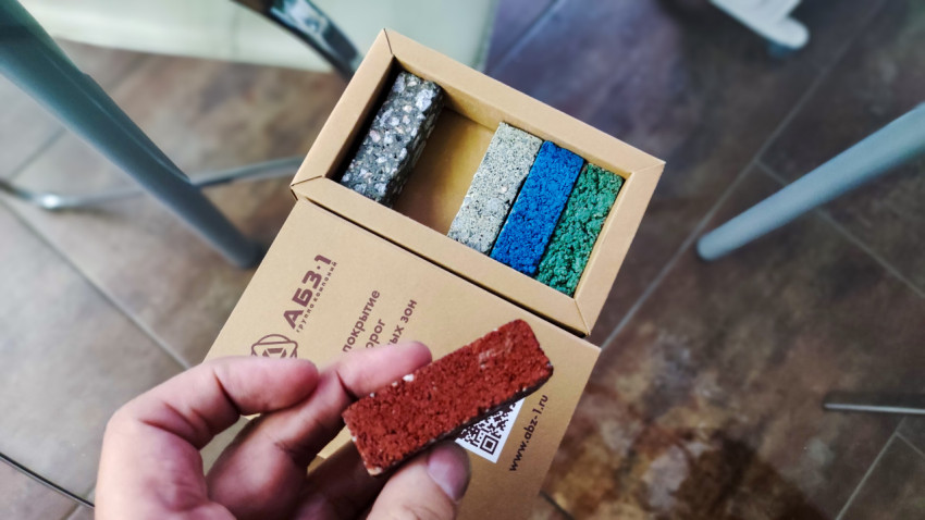 Образец покрытия в руке рядом с демонстрационным набором