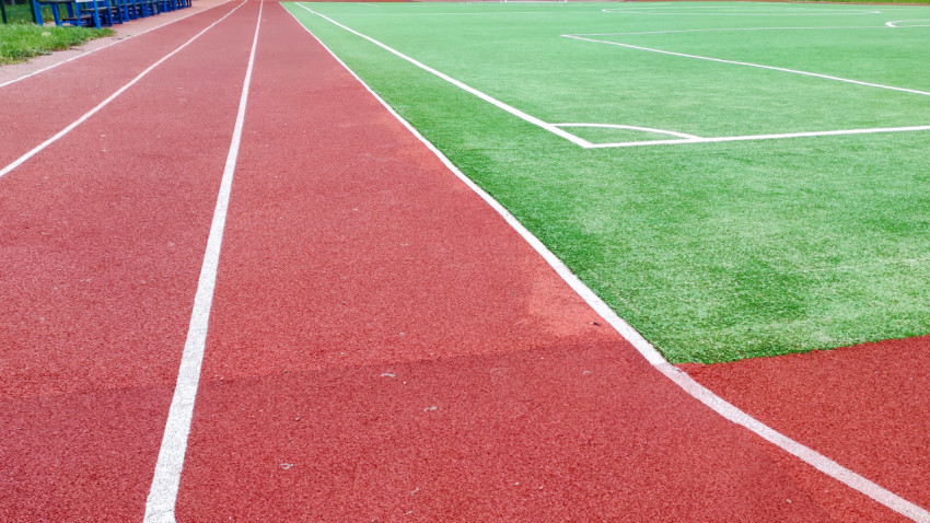 Беговые дорожки рядом с футбольным полем с искусственным покрытием