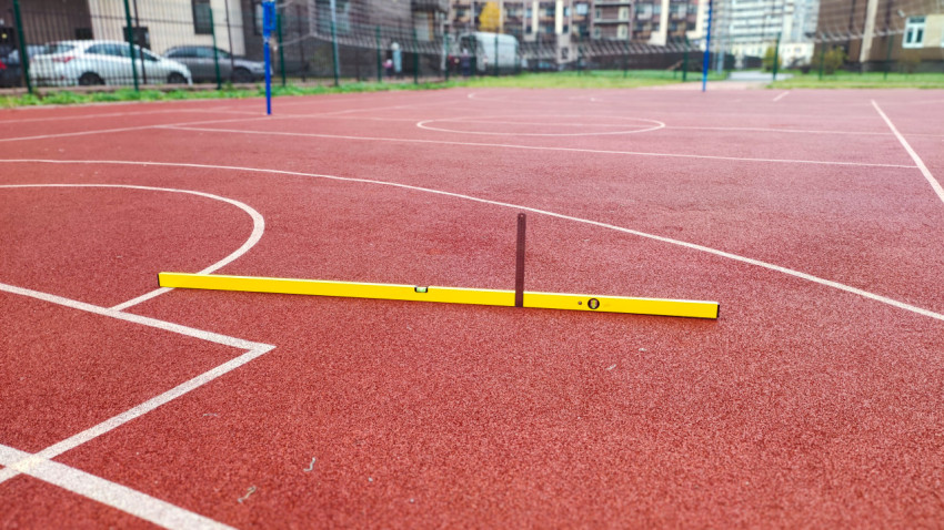 Проверка ровности резинового покрытия спортивной площадки с помощью уровня и линейки