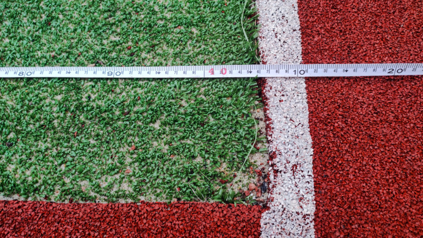 Измерение ширины футбольного поля с помощью измерительной ленты