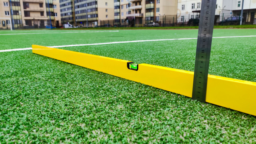 Проверка уклона футбольного поля с использованием уровня и линейки