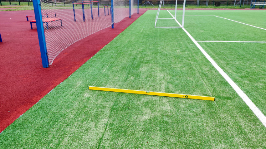 Проверка ровности у кромки футбольного поля рядом с ограждением