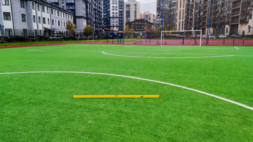 Проверка ровности искусственного футбольного поля строительным уровнем