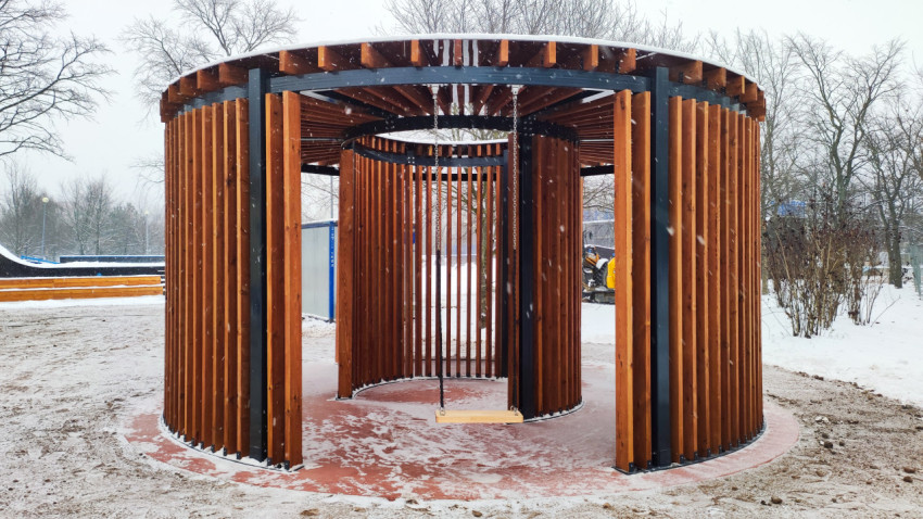 Деревянная беседка с подвесной качелей в зимнем парке