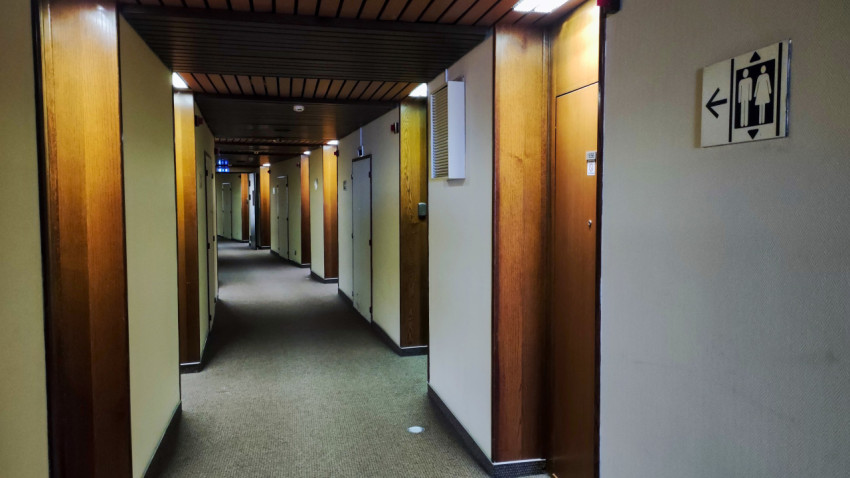 Коридор гостиницы с указателем санитарных помещений