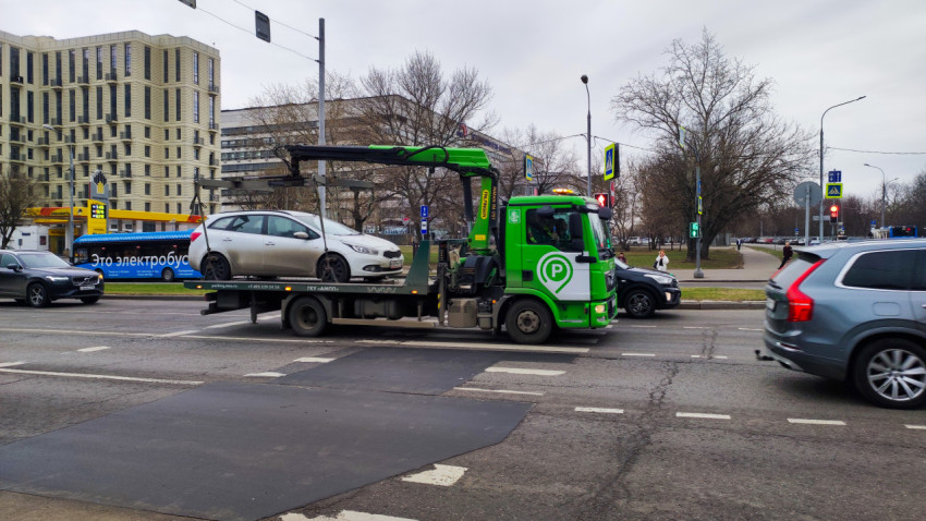 Эвакуатор перевозит автомобиль по городской улице