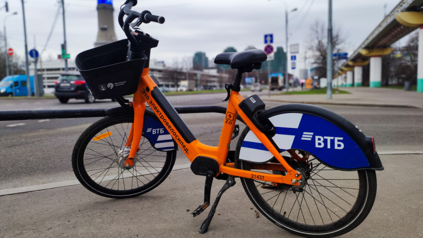 Прокатный электровелосипед ВТБ на улице рядом с городской инфраструктурой