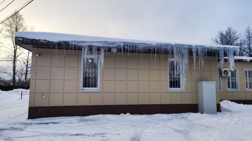 Фасад здания с длинным ледяным карнизом и закрытыми окнами