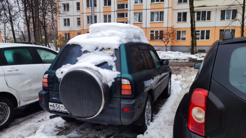 Припаркованный автомобиль с толстым слоем снега на крыше