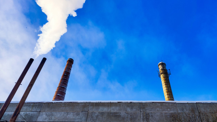 Две дымовые трубы над промышленным зданием зимой