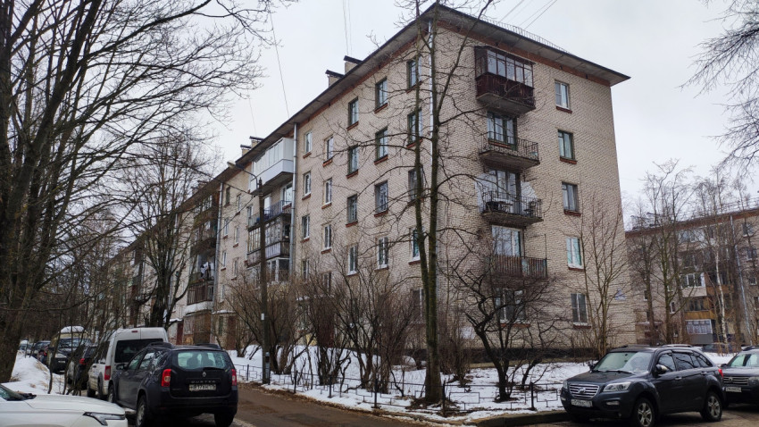 Кирпичный жилой дом советского периода и припаркованные автомобили