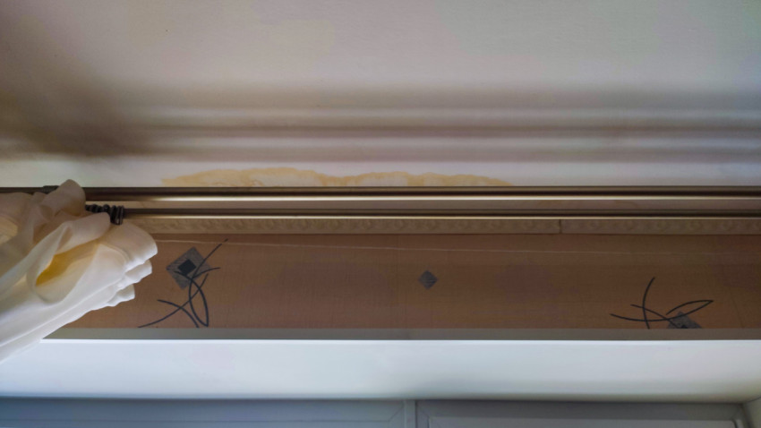 Желтые подтеки на стене над окном внутри комнаты