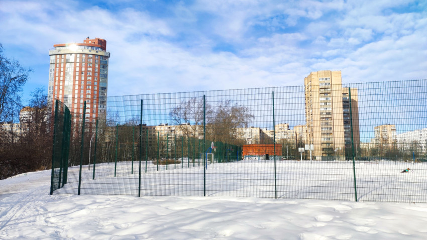 Спортивная площадка с ограждением в жилом квартале зимой