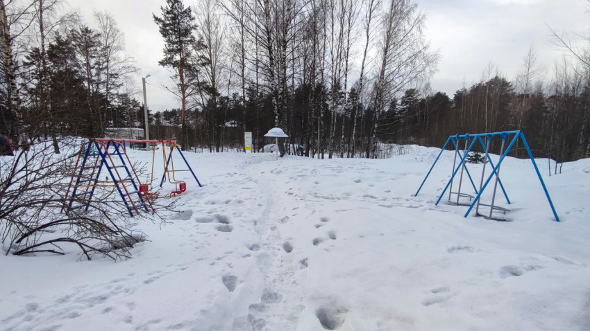 Детская площадка зимой среди деревьев