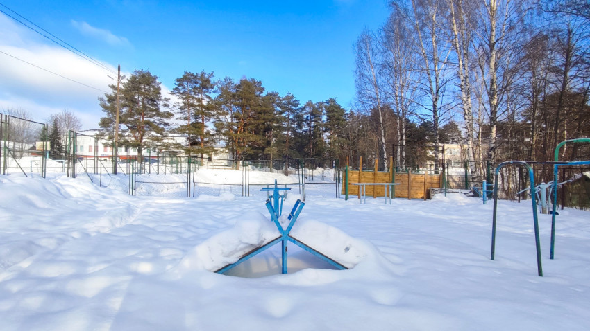 Снежное поле с уличными тренажерами и ограждением
