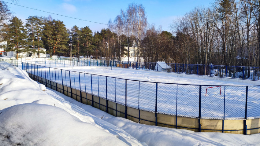 Хоккейная площадка с высокими бортиками в зимнем окружении