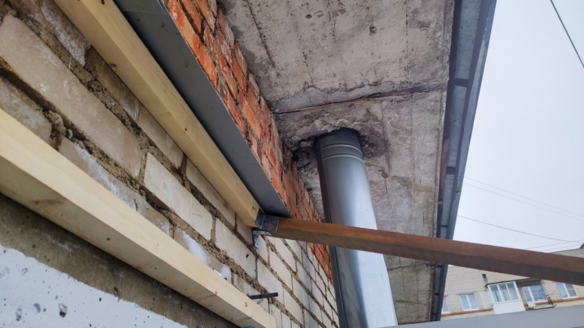 Кирпичная стена и вентиляционная труба под перекрытием балкона