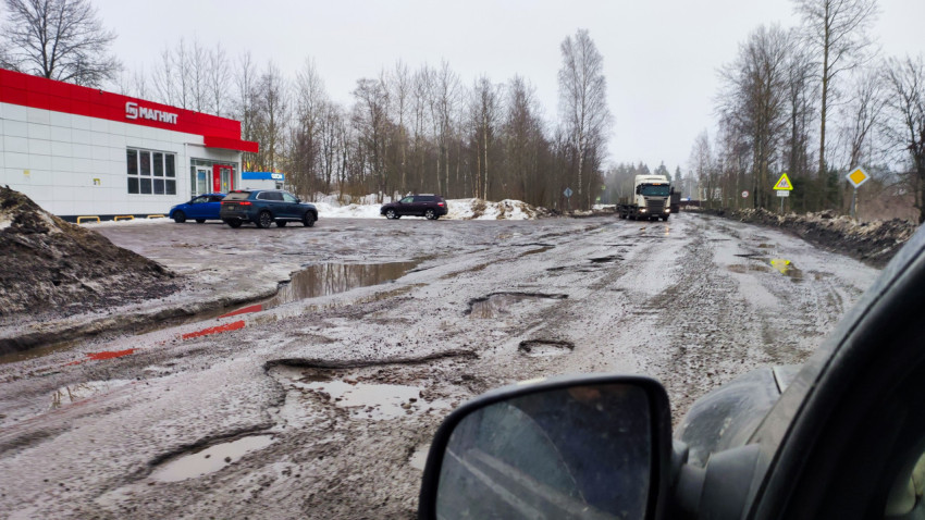 Грунтовая дорога с глубокими колеями у здания магазина