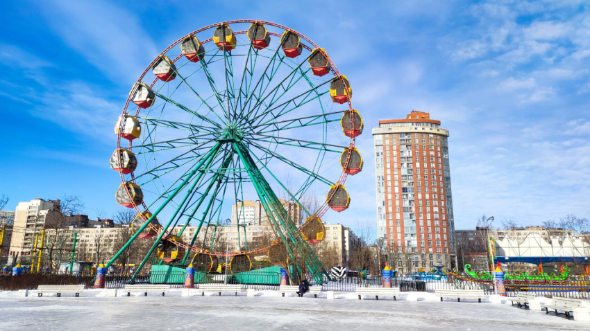 Аттракцион «колесо обозрения» в зимнем парке у жилой башни
