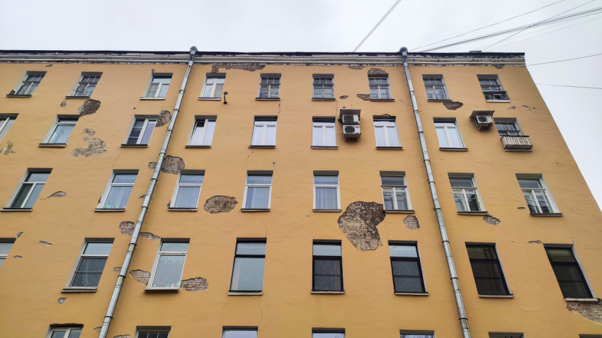 Старый жилой дом с частично осыпавшейся штукатуркой в Санкт-Петербурге