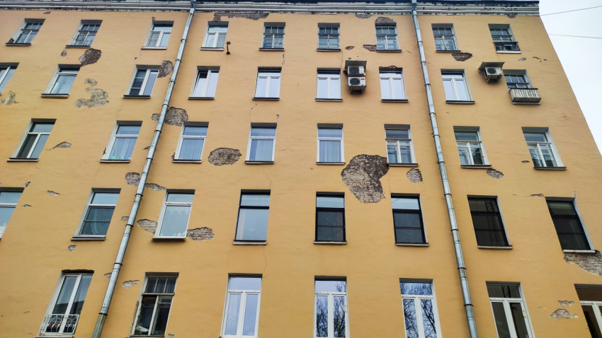 Повреждённая штукатурка на стене многоквартирного дома