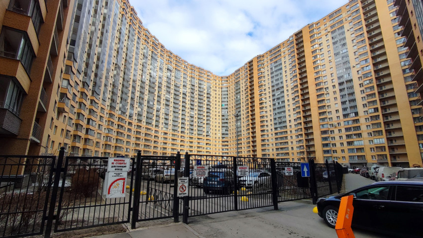 Двор многоэтажного жилого комплекса с парковкой за ограждением