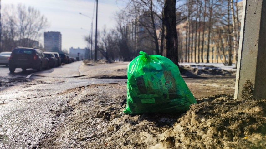 Бытовой мусорный пакет на обочине рядом с пешеходной дорожкой