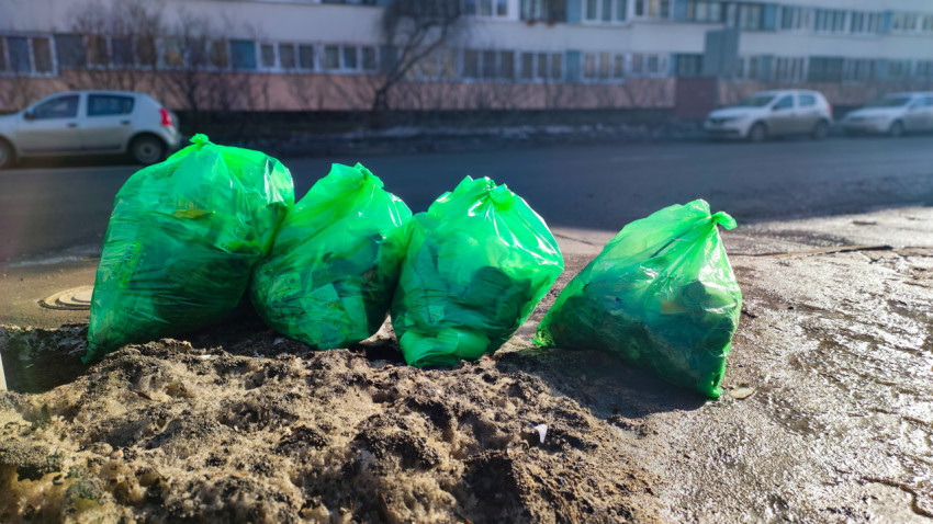 Мешки с мусором на тающем снегу у обочины