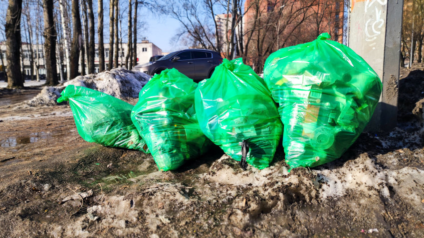Несколько пакетов с отходами на обочине вдоль пешеходной зоны