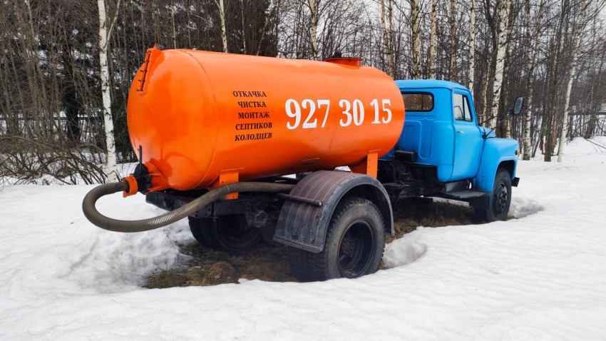 Оранжевая цистерна грузовика крупным планом на фоне зимнего леса