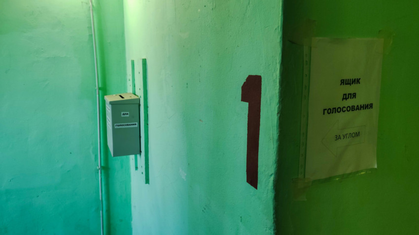 Коридор жилого дома с ящиком для голосования и номером на стене